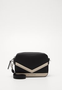 Černá crossbody taška s texturovaným povrchem, zdobená chevronovým vzorem v béžové barvě. Obsahuje odnímatelný popruh a akcenty ze stříbrného kovu.