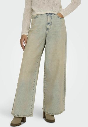 Lichtblauwe wijdvallende jeans van denim met een vervaagde was, onafgewerkte zoom en zichtbare stiksels. Gecombineerd met stevige beigekleurige hoge hakken.
