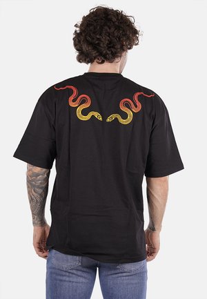T-shirt nera a maniche corte con motivi di serpenti rossi e gialli ricamati sulla schiena, dalla vestibilità rilassata e collo rotondo.