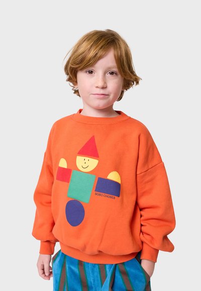 Sudadera naranja con un divertido estampado de personajes geométricos coloridos. La tela parece suave, con un corte holgado y puños acanalados.