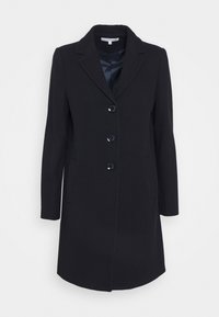 Svart kappa i texturerad tyg med notch-lapel, fem knappar och två sidfickor. Rak siluett.