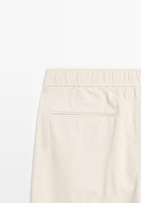 Pantaloni in corda beige con superficie testurizzata, dotati di una vita elasticizzata arricciata e una sola tasca posteriore.
