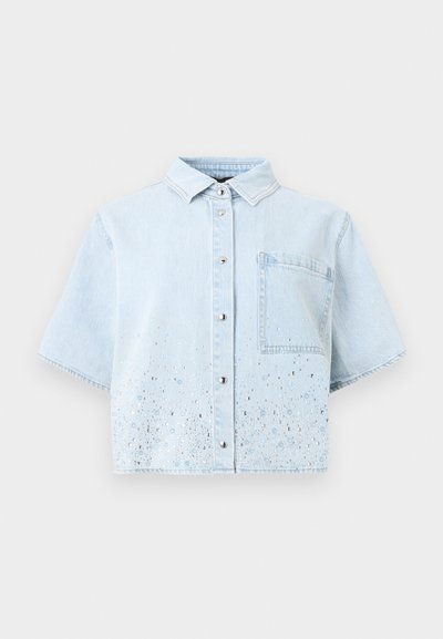 Ανοιχτό μπλε τζιν πουκάμισο με κοντά μανίκια, μπροστινή τσέπη, κούμπωμα με κουμπιά και διάσπαρτες ασημένιες και μπλε πούλιες κοντά στο κάτω τελείωμα.