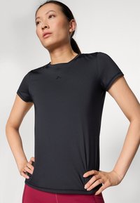 Black moisture-wicking athletic t-shirt with short sleeves, round neckline, slim fit, and a small logo on the chest. Smooth, stretchy fabric.