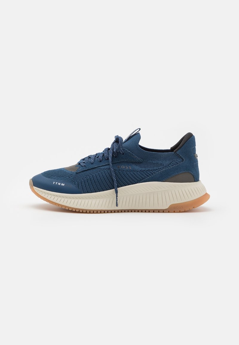 Baskets de sport en tricot bleu avec semelle épaisse blanche, semelle extérieure en caoutchouc, fermeture à lacets à l'avant et logo "BOSS" sur le côté.
