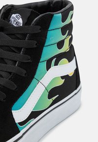 Czarne trampki za kostkę z turkusowym wzorem płomieni, białymi akcentami i teksturowanym zamszowym materiałem. Posiadają czarne sznurowadła i białą gumową podeszwę.