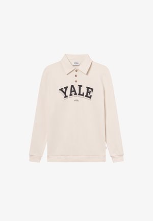 Κρέμα μακρυμάνικη πόλο μπλούζα με γιακά, τρία καφέ κουμπιά, και τη λέξη "YALE" σε έντονη μαύρη γραμματοσειρά στη μέση. Μαλακό ύφασμα.