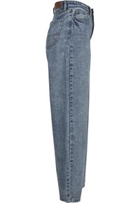 Jean en denim bleu clair avec une coupe droite, cinq poches et une taille haute. Présente des surpiqûres visibles et une patch en cuir à l'arrière.
