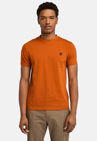 Orange bomulds t-shirt med rund hals og korte ærmer. Har et lille logo på brystet. Glat tekstur og normal pasform.
