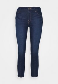 Jeans skinny de mezclilla azul oscuro con una cintura de altura media, cinco bolsillos y detalles de costura marrón. Textura suave con un desvanecimiento mínimo.