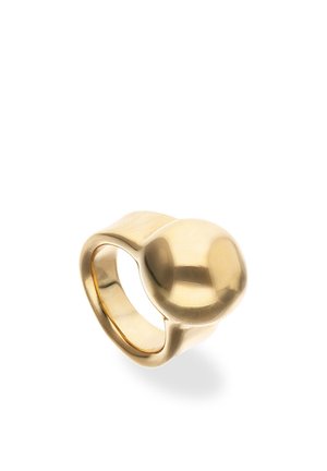 Anillo de metal color dorado con una banda ancha y una gran cúpula lisa y redondeada en la parte superior, mostrado sobre un fondo blanco.