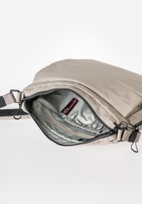 Zaino beige con un'esterno liscio, chiusura con zip e interni caratterizzati da una fodera chiara e una tasca con zip.