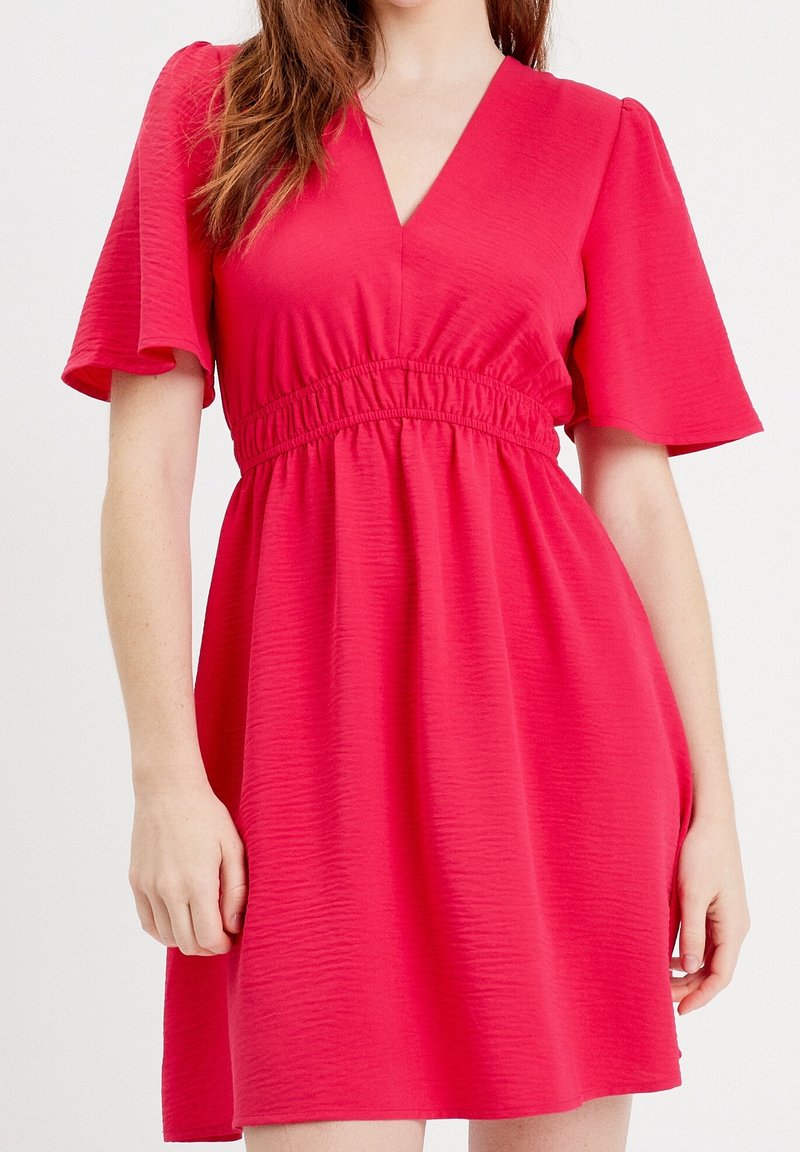 Robe courte rose avec manches courtes évasées, encolure en V et taille élastiquée. Tissu texturé avec une coupe décontractée, se terminant au-dessus du genou.