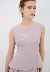 Top peplo lilla realizzato in tessuto texturizzato, con scollatura rotonda e dettagli di cucitura angolari, dotato di un corpetto aderente e orlo svasato.