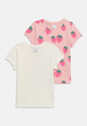 Deux t-shirts enfants à manches courtes, un uni blanc et un rose avec des motifs de fraises souriantes.