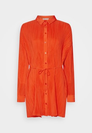 Langärmliges, orangefarbenes, plissiertes Hemdblusenkleid mit durchgehender Knopfleiste, Kragen und Taillengürtel vor weißem Hintergrund.