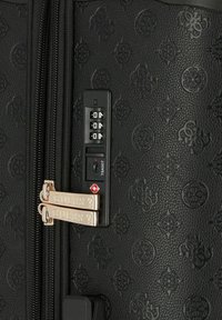 Valigia nera texturizzata con motivi in rilievo. Presenta cerniere dorate con la scritta "GUESS", una serratura a combinazione e una serratura TSA per la sicurezza.