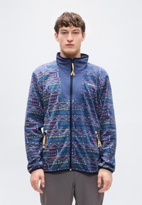 Ζακέτα από φλις με γεωμετρικά σχέδια σε μπλε, ροζ και κίτρινο. Διαθέτει ψηλό γιακά, φερμουάρ μπροστά και πλαϊνές τσέπες με κλείσιμο με φερμουάρ.