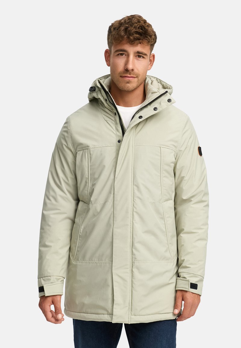 Lys grønn polstret parkas med hette, som har trykknapper, to frontlommer og elastiske mansjetter. Materialet ser glatt og vanntett ut.