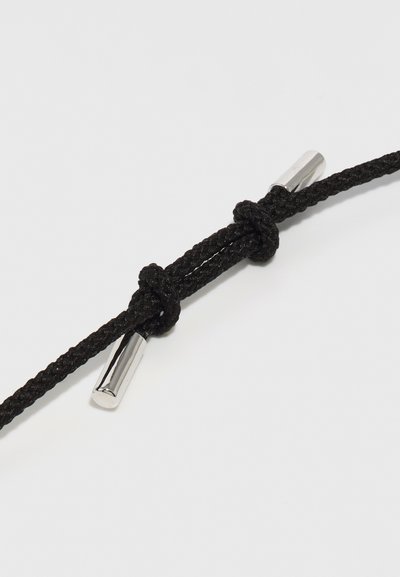 Corda intrecciata nera con un nodo e accenti metallici cilindrici ad ogni estremità. Il materiale sembra resistente e con una texture.