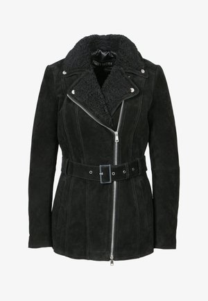 Musta mokkatakkia, jossa on lammasvillakaulus, vyötärölle kiristettävä vyö ja hopea vetoketju. Ominaisuuksia ovat pystysuorat saumat ja sivutaskut.