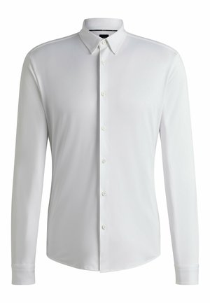 Camisa blanca de manga larga fabricada en tejido suave, con cuello puntiagudo, cierre de botones completo y dobladillo redondeado con puños abotonados.