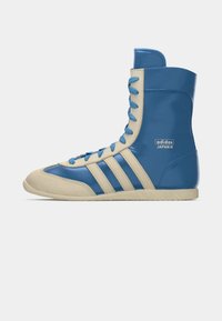 High-top athletic shoes in blue leather with beige accents, featuring three diagonal stripes, blue laces, and a rubber sole.
