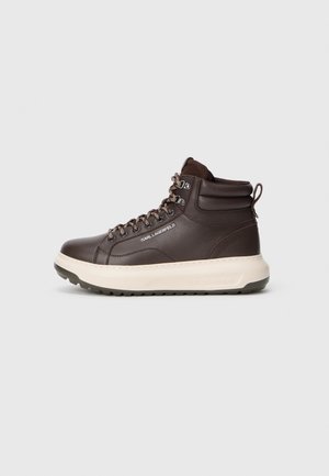 Dunkelbrauner High-Top-Ledersneaker mit gepolstertem Knöchel, weißer dicker Sohle, gemusterten Schnürsenkeln und "KARL LAGERFELD"-Branding an der Seite.