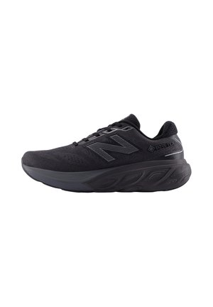Schwarzer New Balance Laufschuh mit dicker Sohle, Mesh-Obermaterial, Gore-Tex-Label und "N" Logo auf der linken Seite.