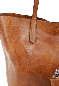 Bruine leren tote bag met een gestructureerd oppervlak, voorzien van twee stevige handvatten en een accentdetail met een metalen sluiting.