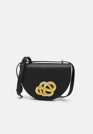 Sac en cuir noir de forme arrondie, avec un grand nœud décoratif doré à l'avant et une bandoulière réglable.