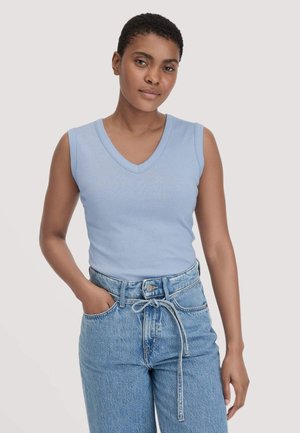 Hellblaues ärmelloses V-Ausschnitt-Top, kombiniert mit hoch taillierten hellen Jeans aus Denim, mit einem vorderen Knoten und umgeschlagenen Ärmelends. Einfache, glatte Textur.