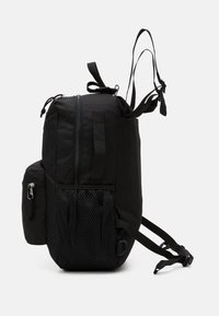 Sac à dos noir en tissu durable, avec une fermeture éclair centrale, une poche latérale en filet et des bretelles réglables. Design compact avec un matériel minimal.
