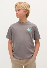 Graues kurzärmliges T-Shirt aus Baumwolle mit einem hellblauen Handabdruck-Design auf der linken Brustseite. Rundhalsausschnitt, lockere Passform.