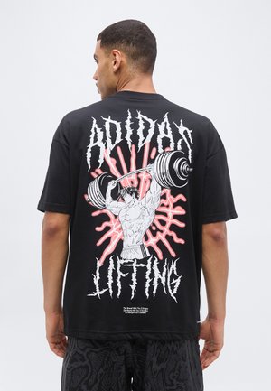 Homme portant un t-shirt noir Adidas avec un graphisme d'une silhouette musclée soulevant une barre et un texte en gras "Adidas Lifting" au dos.
