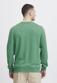 Felpa verde realizzata in tessuto morbido. Presenta maniche lunghe, scollo rotondo, polsini a costine e una vestibilità comoda. Design semplice.