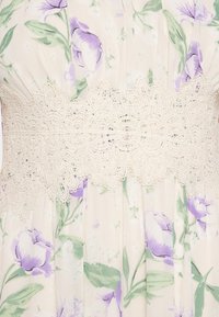 Tissu crème avec imprimé floral violet clair et large bande de dentelle ivoire avec des motifs floraux détaillés autour de la taille.