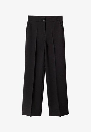 Femme portant une veste en cuir noire sur un pull blanc avec des losanges gris foncé et des lignes croisées, associée à un pantalon noir.
