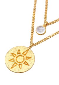 Collana in metallo dorato con pendant rotondo raffigurante un design solare e un piccolo ciondolo rotondo con una pietra trasparente, entrambi su catene collegate.
