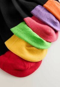 Čierne ponožky s rôzne sfarbenými špičkami v červenej, žltej, zelenej, ružovej, fialovej a oranžovej farbe, usporiadané vedľa seba na bielom povrchu.