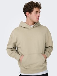 Sweat à capuche beige avec une poche kangourou, des poignets et un ourlet côtelés, offrant une coupe décontractée et une capuche spacieuse. Texture de tissu lisse et douce.