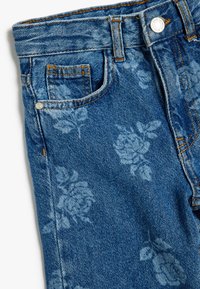 Jeans de mezclilla azul con un patrón floral en tonos más claros, con un diseño clásico de cinco bolsillos y costuras naranjas.