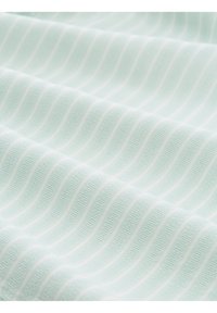 Gros plan d’un tissu bleu clair avec des rayures ondulées subtilement en relief créant un motif texturé sur la surface.