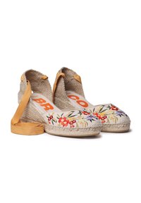Vyšívané espadrilové wedge sandále z béžovej látky s kvetinovými vzormi, jute podrážkou a žltými látkovými viazaniami na členkoch. Logo vytlačené v oranžovej farbe.