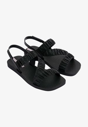 Czarne sandały z teksturowaną gumową podeszwą, z marszczonymi paskami z materiału i minimalistycznym designem. Regulowany pasek na pięcie dla lepszego dopasowania.