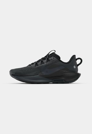 Chaussure de sport noire avec un dessus en maille texturée, des lacets plats et une semelle rembourrée. Présente un branding subtil et une silhouette épurée.