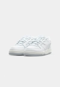 White athletic sneakers with a textured mesh and synthetic leather upper, featuring gray accents and a padded collar, flat laces, and rubber sole.