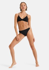 Black bikini set featuring a triangle top with thin straps and matching low-rise bottoms. Made from smooth, stretchy fabric, minimal design.