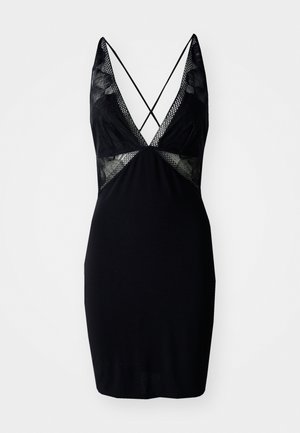 Svart kjole med blonder og mesh-detaljer, med dyp V-hals, tynne stropper i kryssmønster, og en tettsittende silhuett.