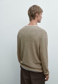 Hellbrauner, lockerer Strickpullover mit gerippten Bündchen und Rundhalsausschnitt. Der strukturierte Stoff wirkt weich und bequem.